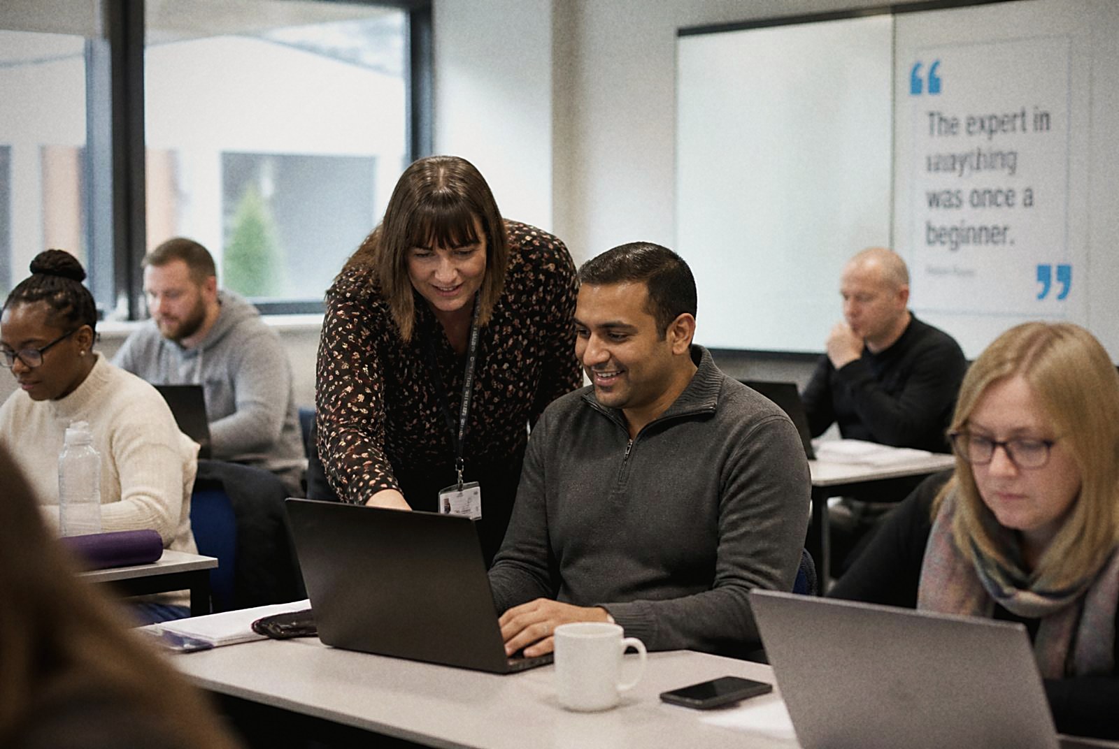 Adult learners working with laptops in a training room